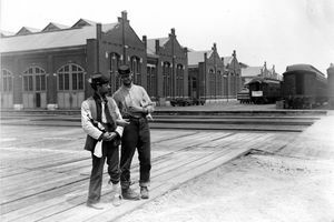 Два војника стоје поред зграде Пуллман и тренирају аутомобиле са закључаним рукама и боцом алкохолних пића током чикашког штрајка Пуллмана 1894. године