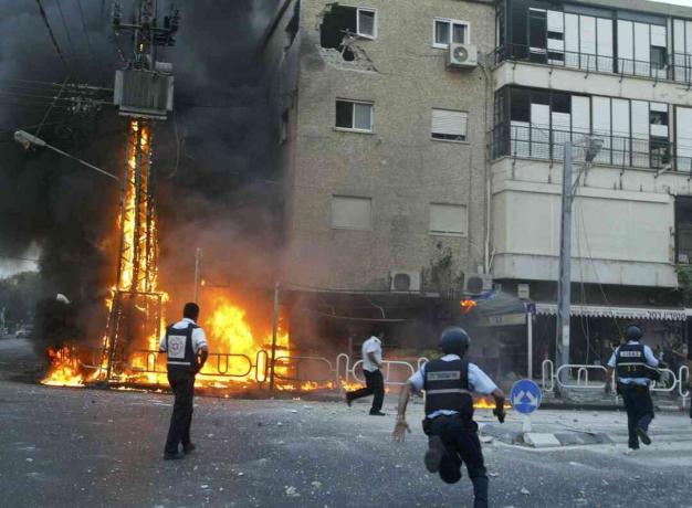 Израелски полицајци појурили су на место запаљеног стуба струје и оштетили зграду моменте након што је волеј ракета Хезболлах погодио 13. јула 2006. године у северном граду Нахарииа, у Израелу.