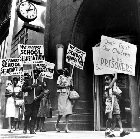 Демонстранти, међу њима и дечак, протестују испред канцеларије школског одбора у знак протеста због сегрегације.