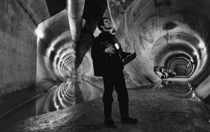 Човек који стоји на месту где се у тунелу спајају два тунела.