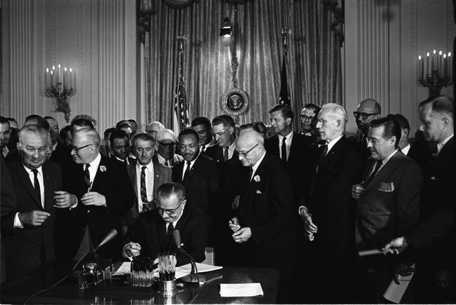 Председник Линдон Б. Џонсон потписује Закон о грађанским правима из 1964. као Мартин Лутер Кинг, млађи, и други, погледајте.