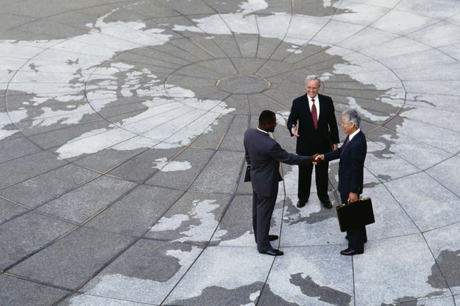 Економски регионализам: Бизнисмени се рукују на мапи света.